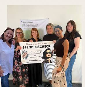 Quelle: Diakonisches Werk Karlsruhe Eine Gruppe von Frauen hält einen großen Spendenscheck für den Kinderhospizdienst